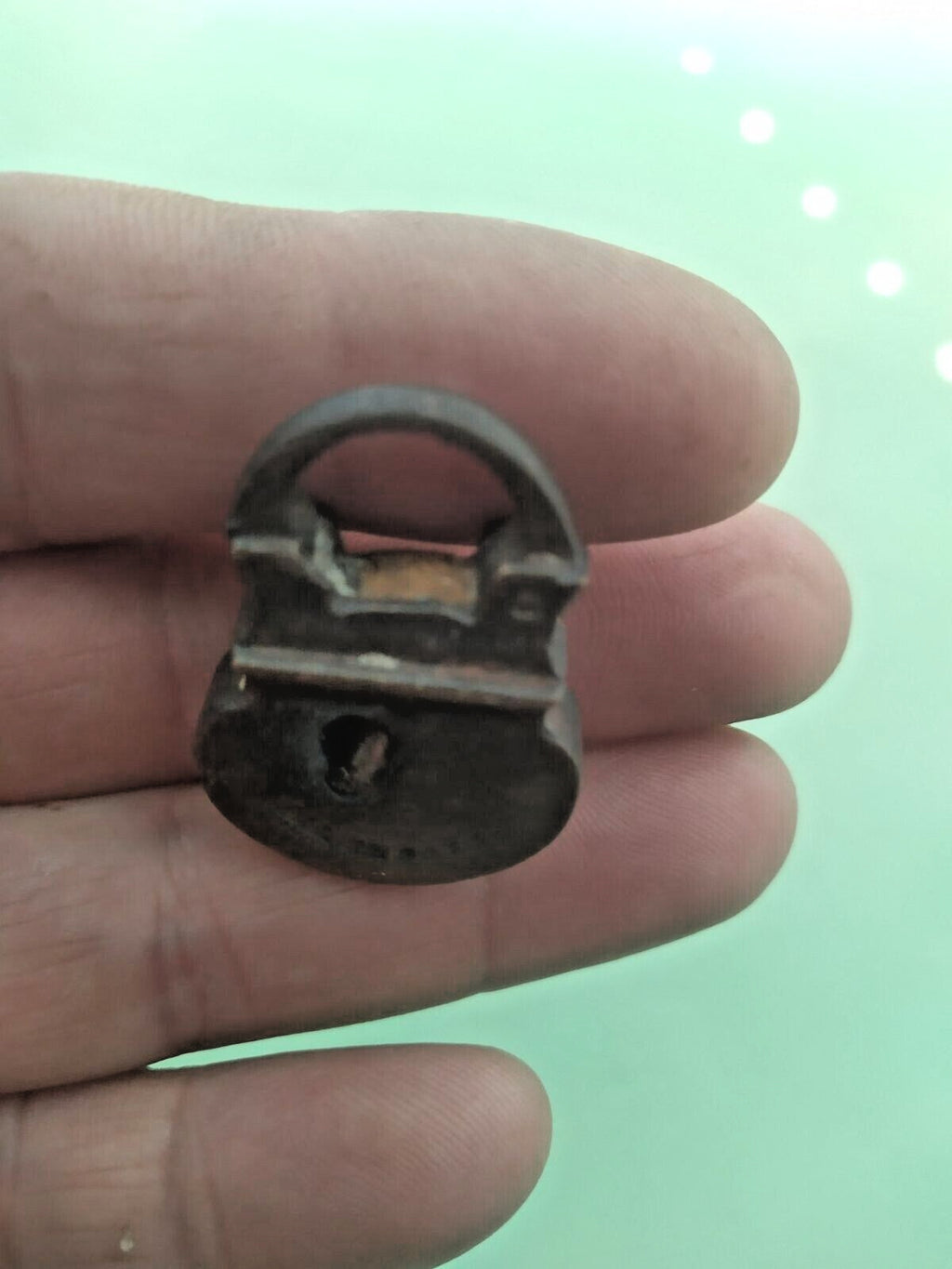 Miniature brass padlock held in fingers for scale – detail 9