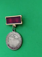 Gold-tone aluminum Soviet medal-style pin with Cruiser Aurora and laurel wreath