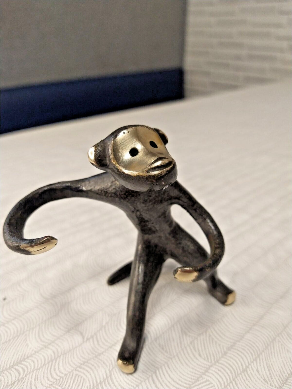 Bronze monkey salt and pepper holder with long curved arms and polished brass face