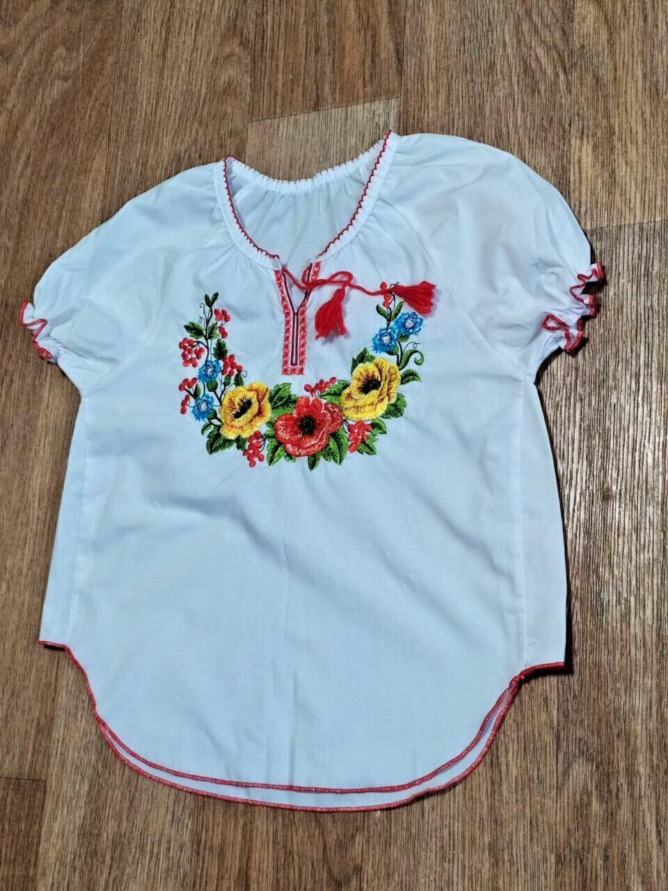 Ukrainian embroidered blouse neckline with red tassels and cross-stitch