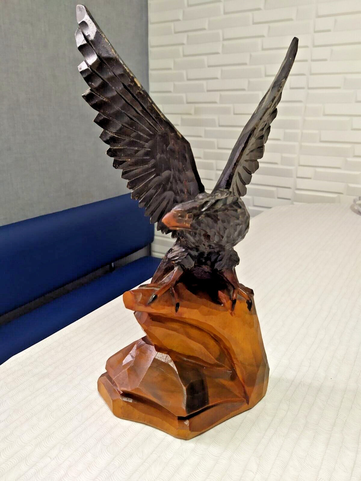 Hand carved wooden eagle statue with spread wings above a rocky cliff