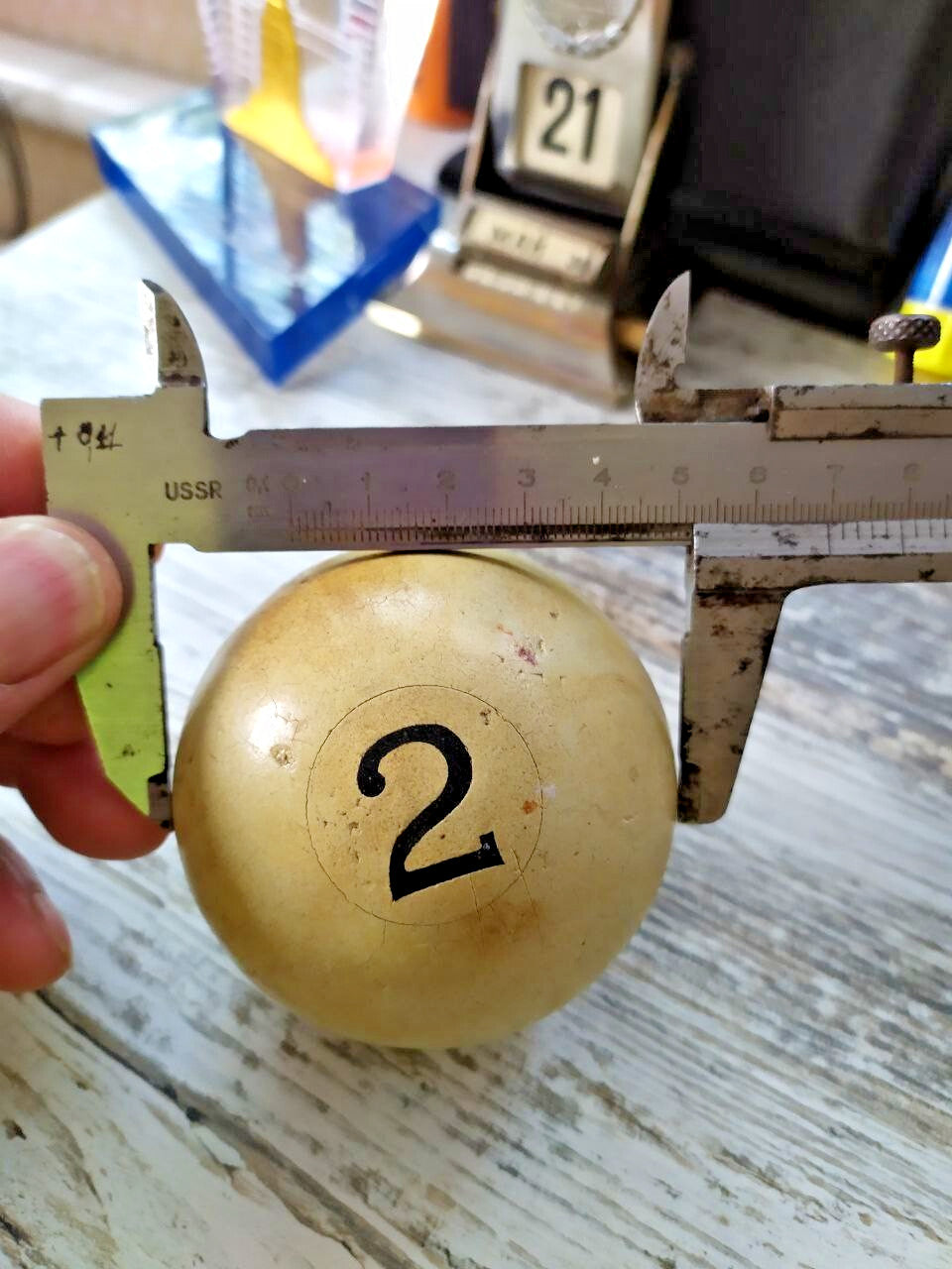 Old Soviet billiard ball next to a caliper showing about 67 mm diameter – detail 7