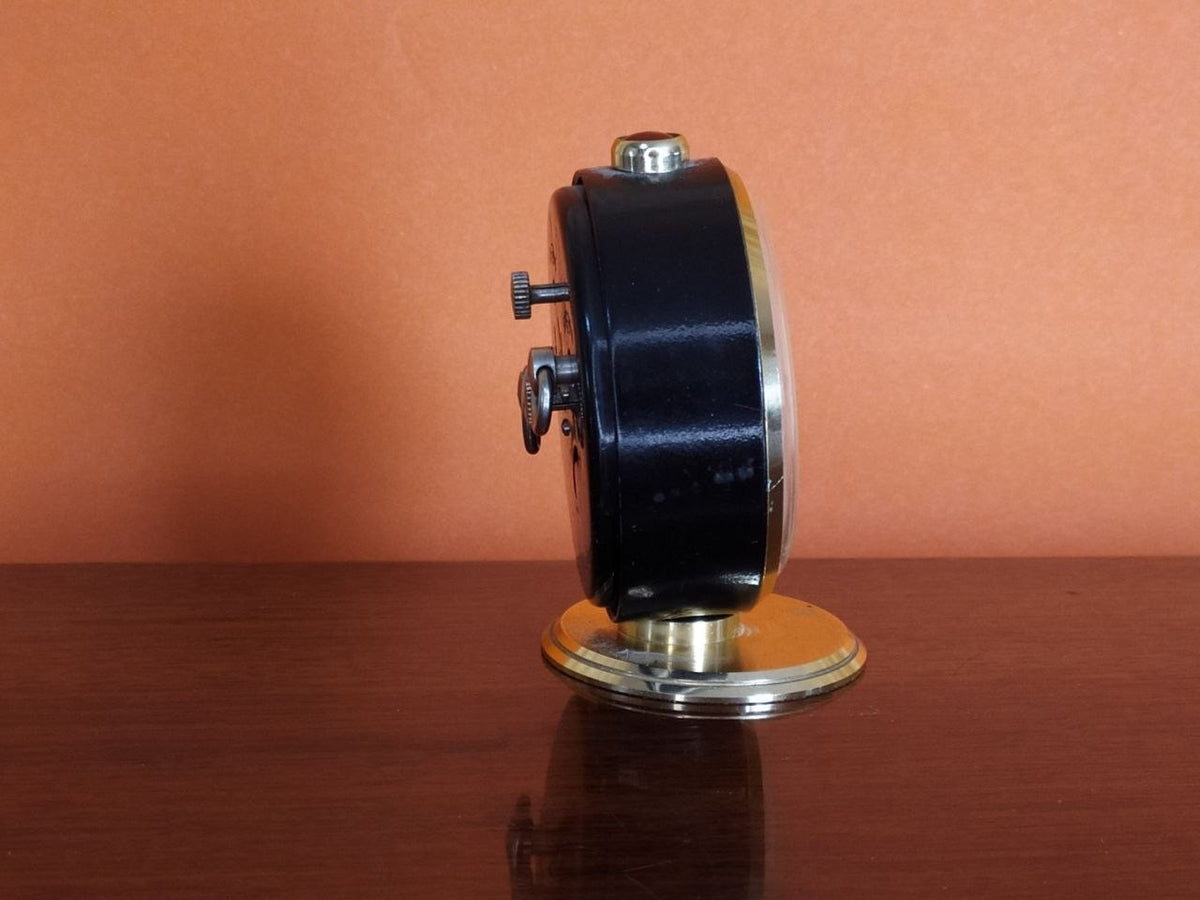 Mechanical Soviet alarm clock with gold-colored stand and matte black case