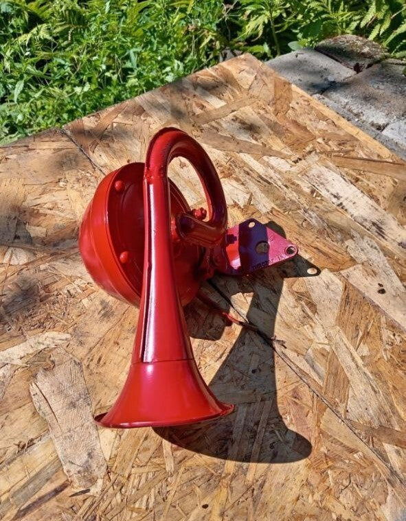 Red electric horn next to a measuring tape, about 25 cm long