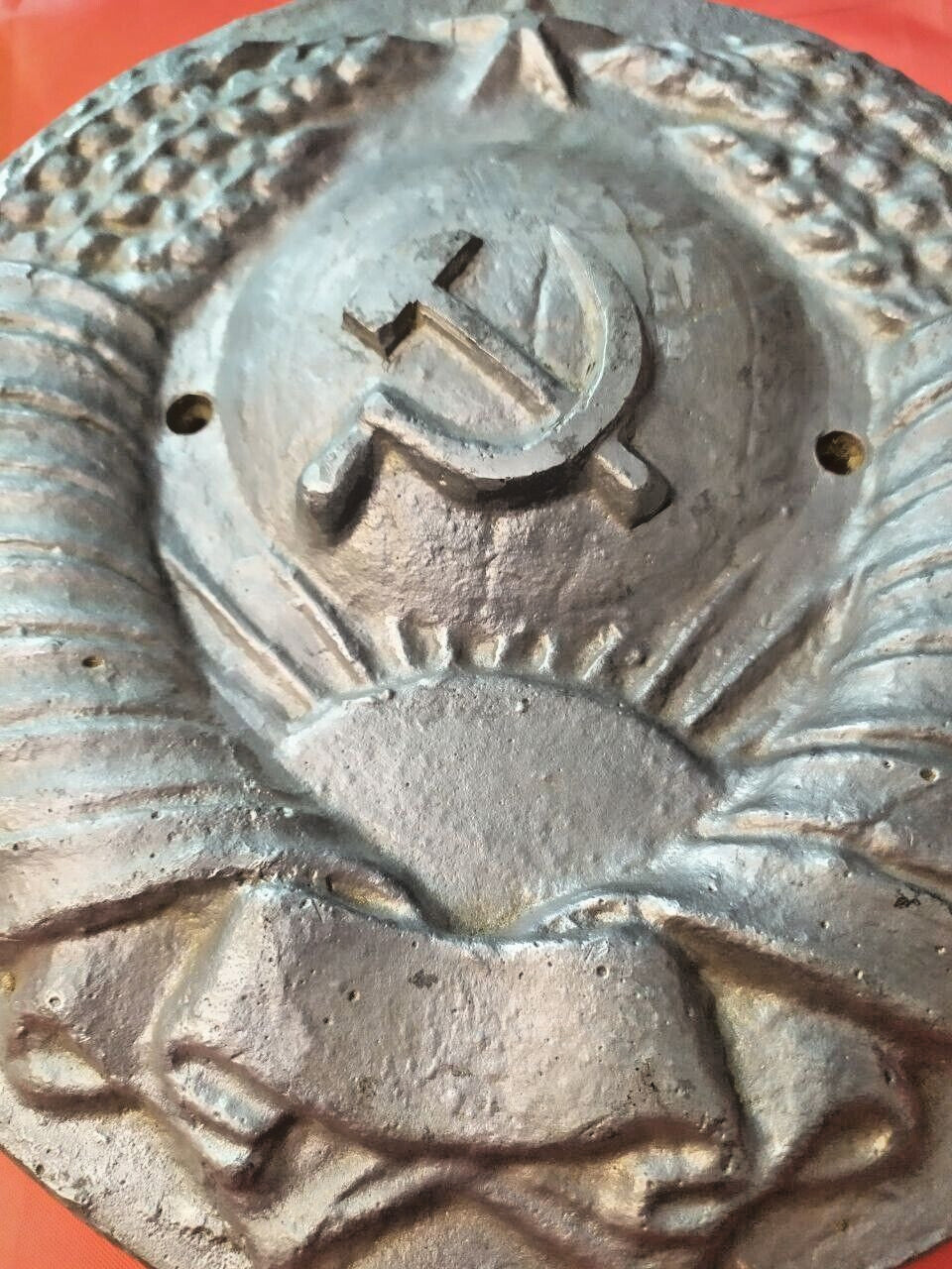 Cast metal Soviet crest showing two mounting holes on the sides