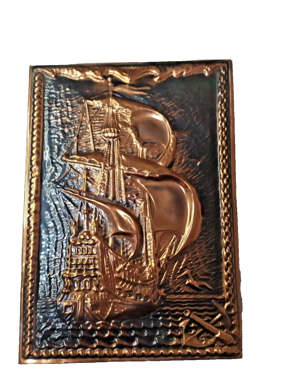 Vintage copper plaque showing natural patina and wave detail