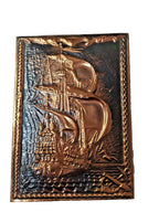 Vintage copper plaque showing natural patina and wave detail