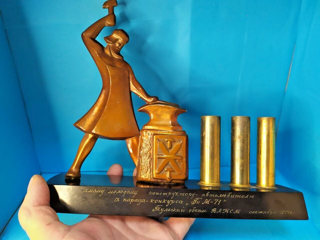 Soviet blacksmith figure at anvil with crossed hammers emblem