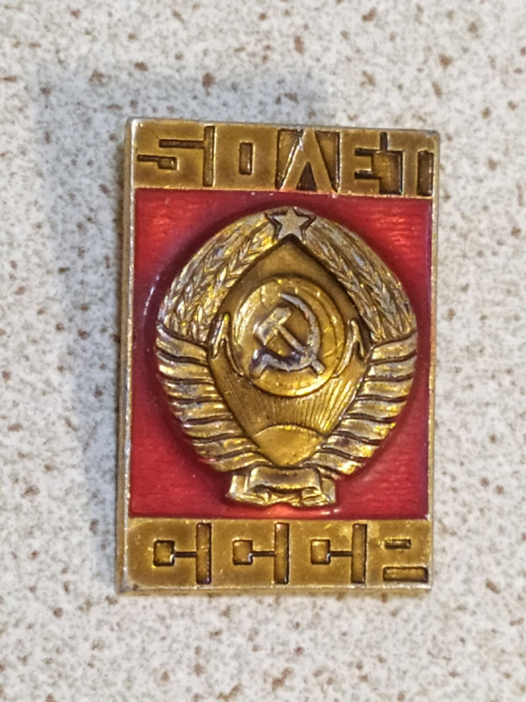 Gold-tone Soviet emblem pin with red enamel and 50 Years inscription