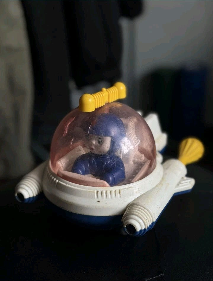 Soviet space collectibles: vintage plastic rocket toy with cosmonaut in a clear dome