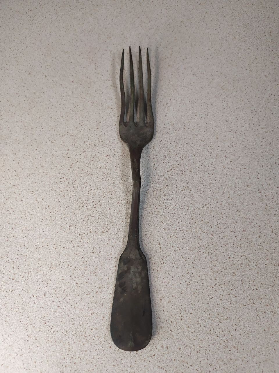 Antique Russian copper alloy dinner fork on a scale showing 67 grams