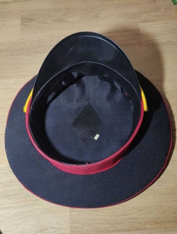 Golden braided cord and brass-tone buttons on the militia uniform cap