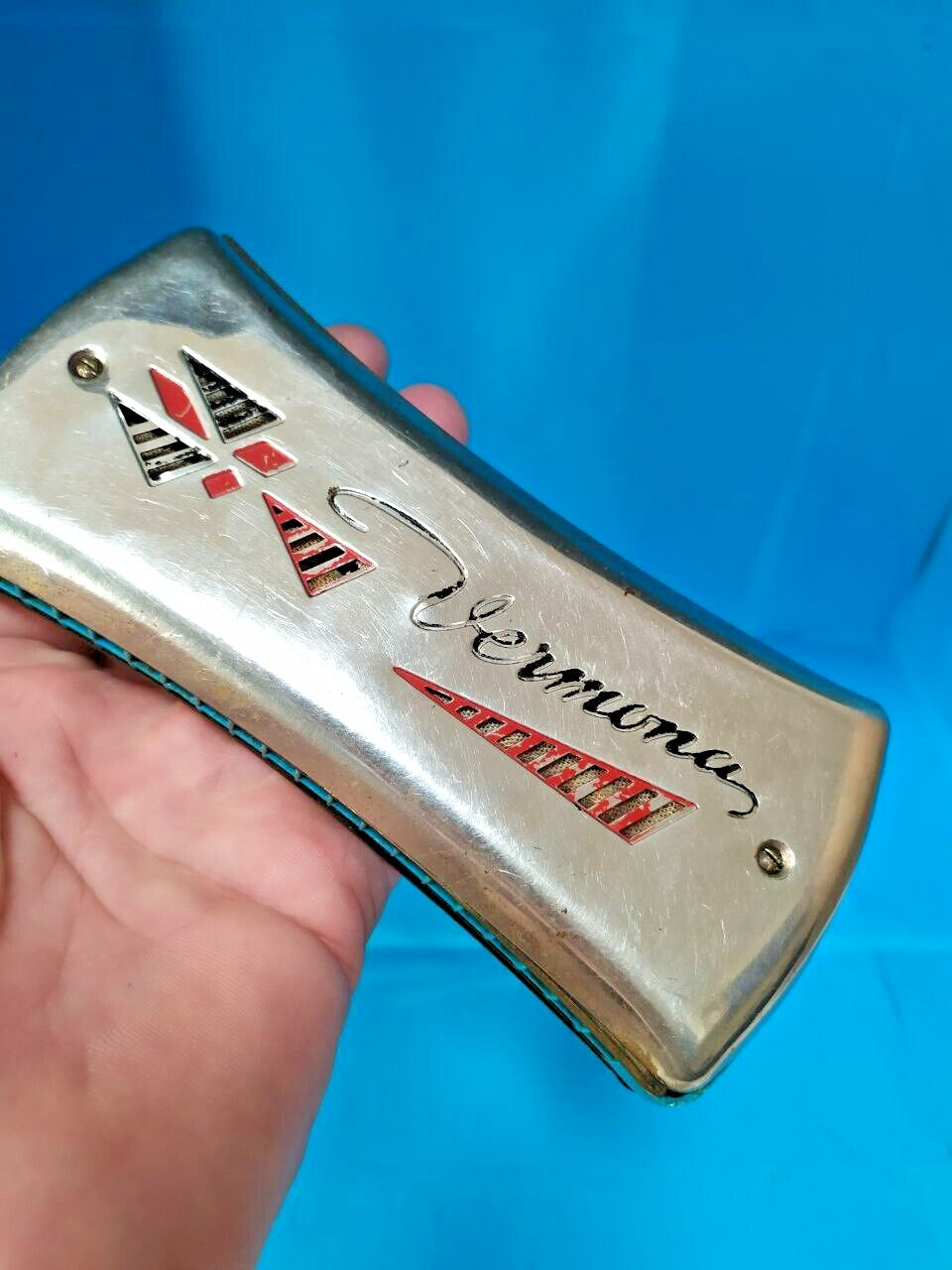 Pocket-size East German Vermona harmonica shown against a hand for scale – detail 16