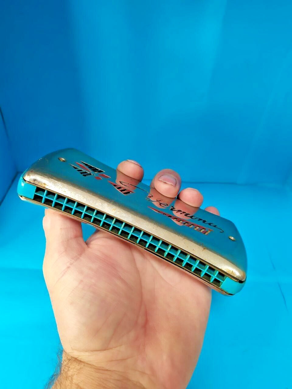 Pocket-size East German Vermona harmonica shown against a hand for scale – detail 19
