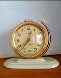 Vintage Soviet alarm clock Slava with gold-tone globe case on a white base
