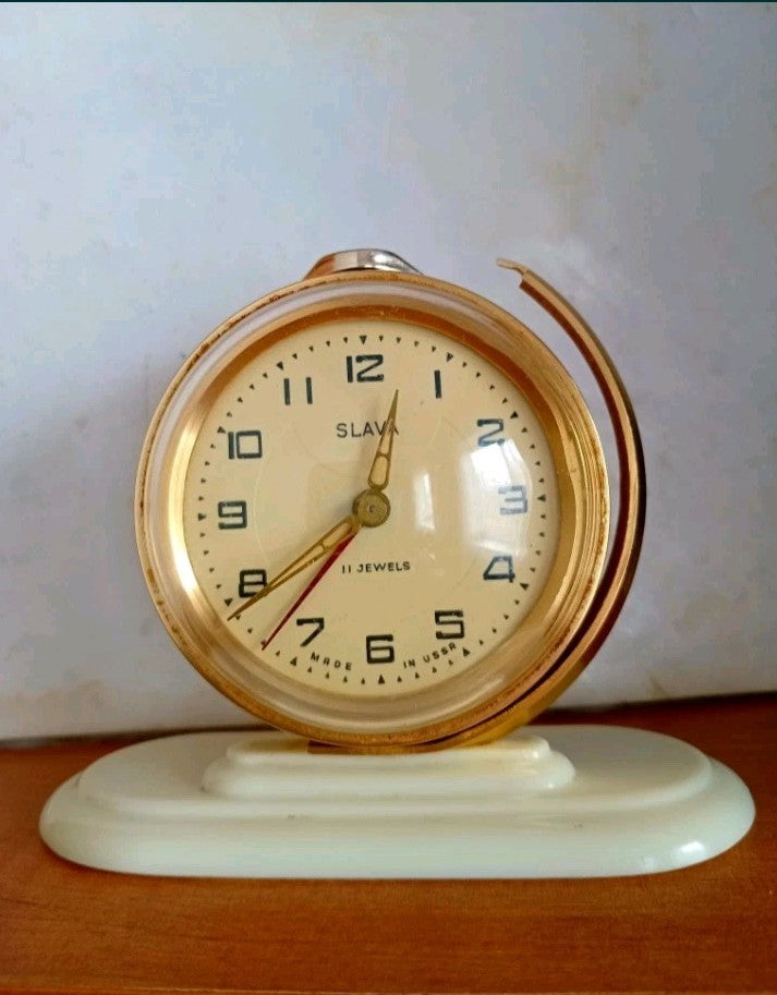 Vintage Soviet alarm clock Slava with gold-tone globe case on a white base