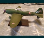 Wooden airplane model on dark rectangular display stand with tape measure