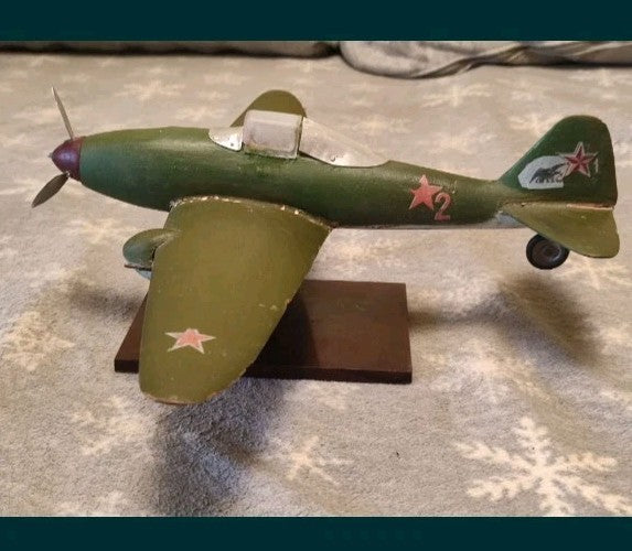 Wooden airplane model on dark rectangular display stand with tape measure
